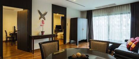 A modern hotel room with a dining area, a sofa, and a large window with curtains.