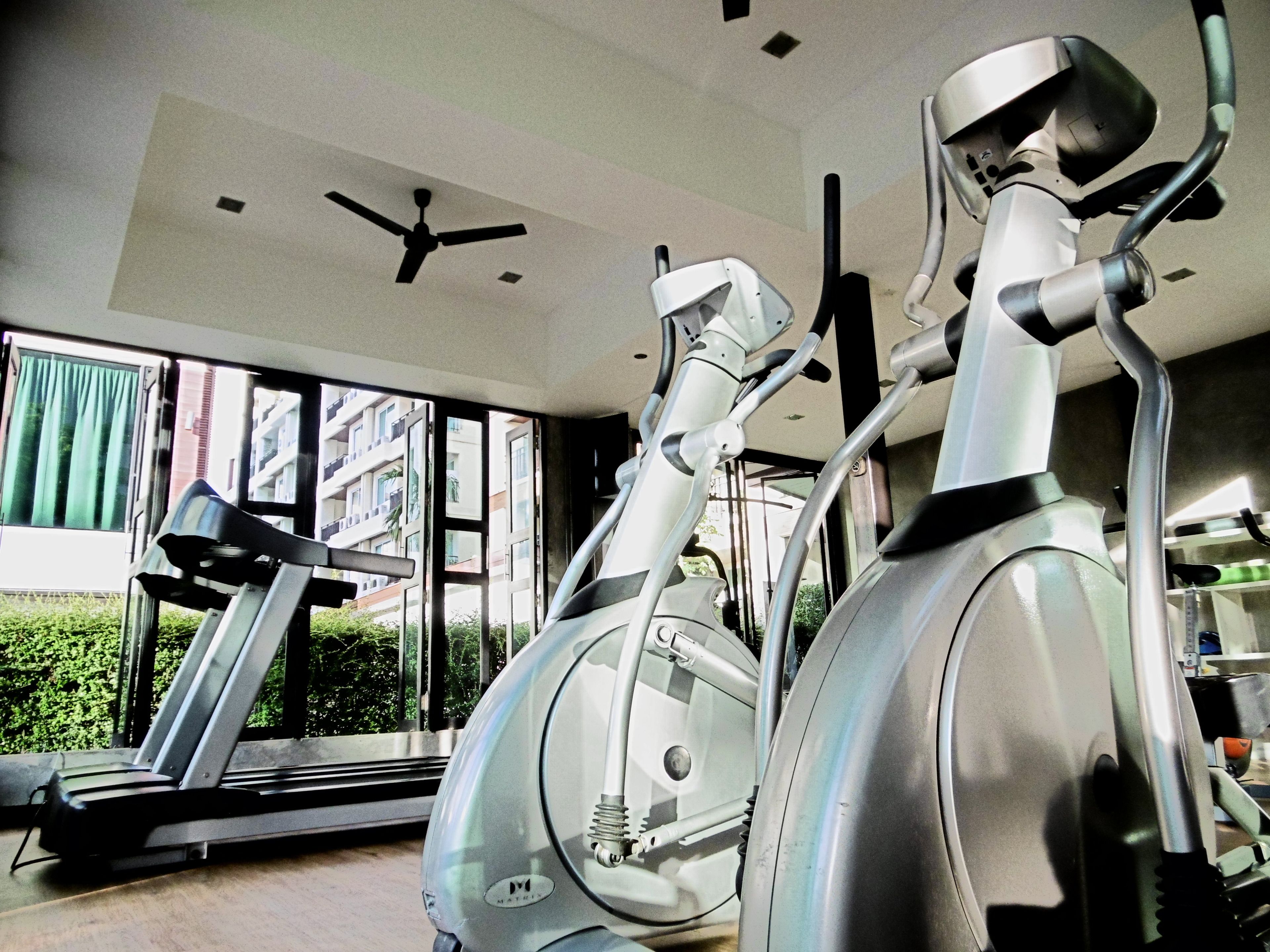 A gym with stationary bikes, a treadmill, and a ceiling fan.
