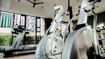 A gym with stationary bikes, a treadmill, and a ceiling fan.