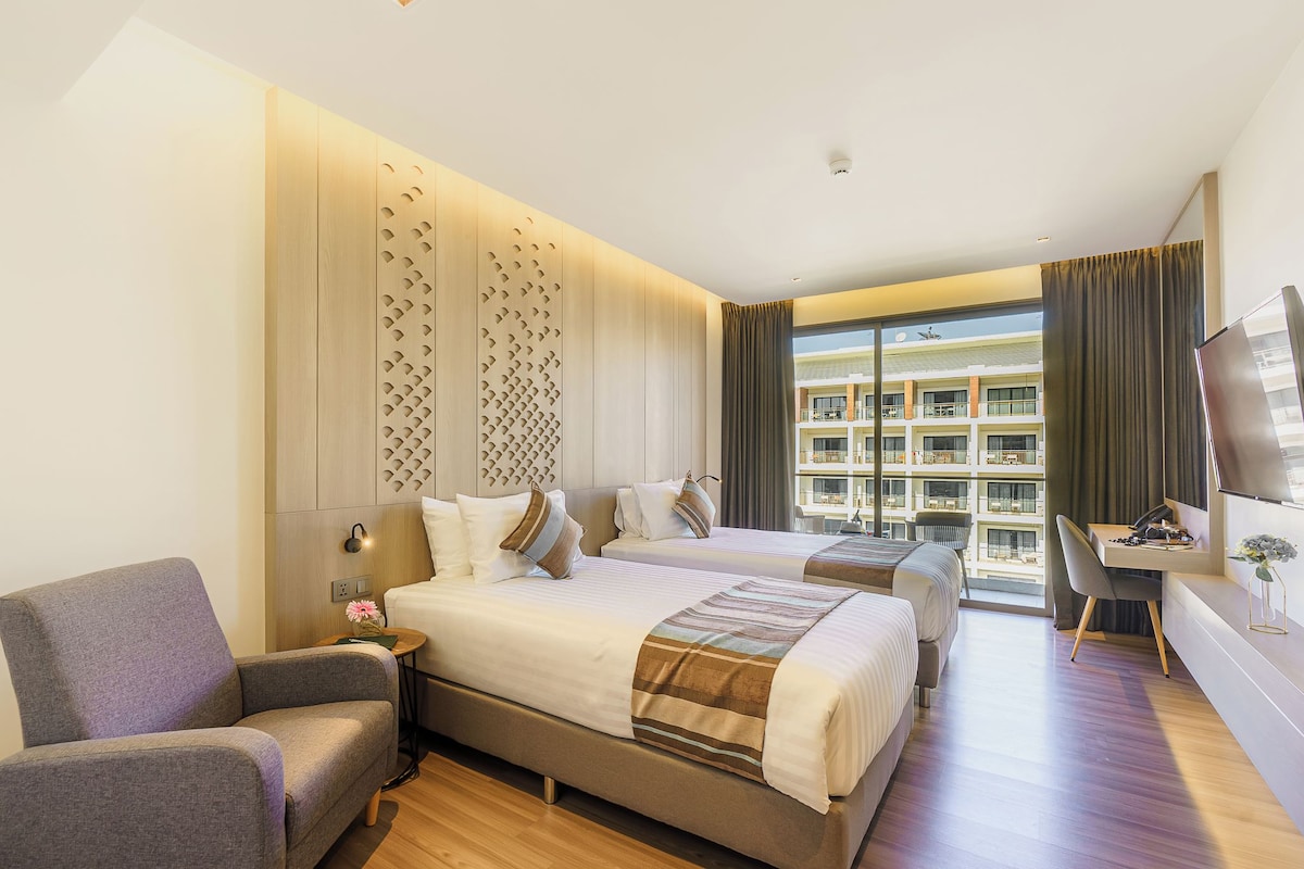 Ein Hotelzimmer mit einem großen Bett, einem Schreibtisch, einem Stuhl und einem Fernseher.