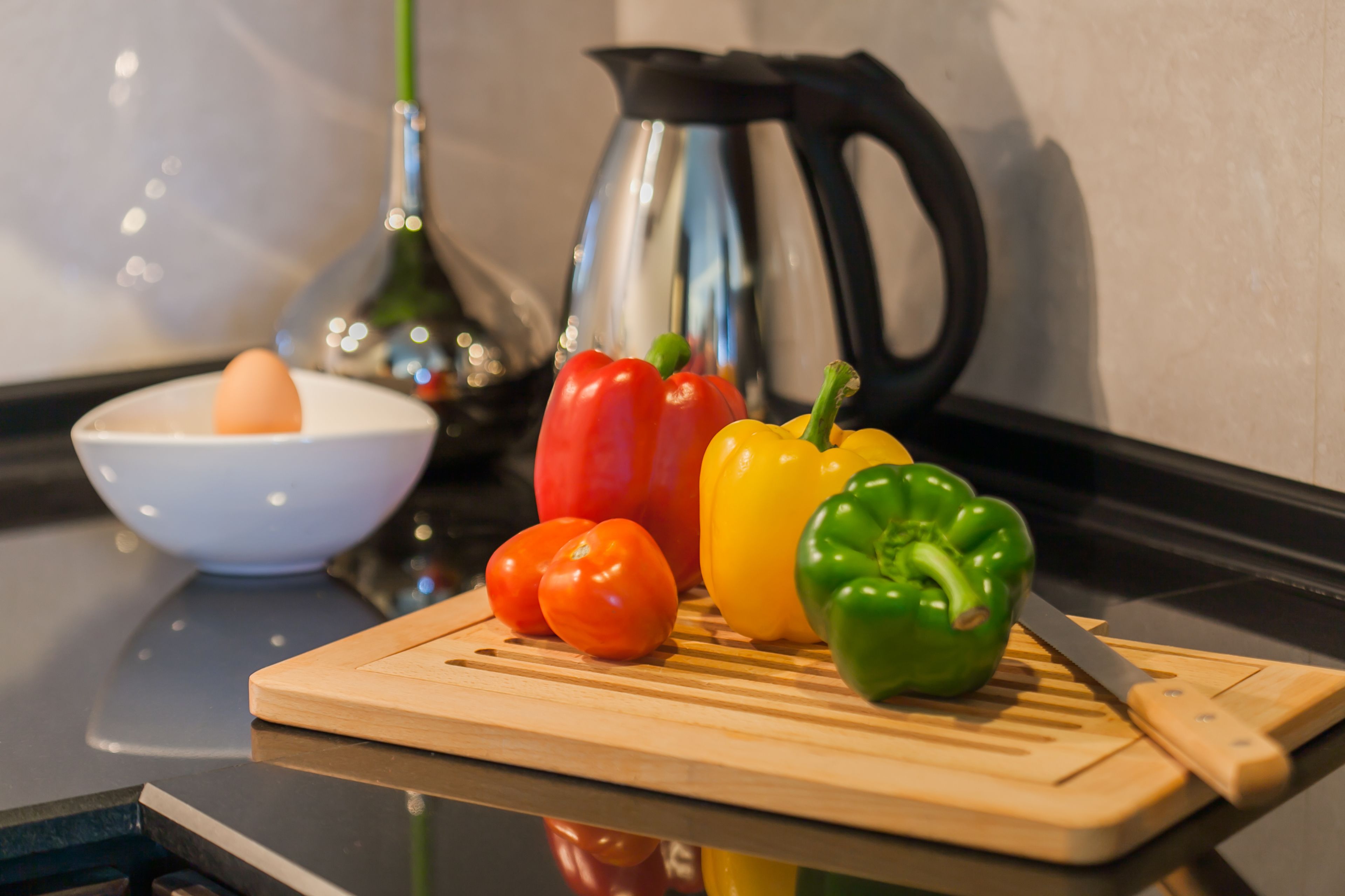 A kitchen counter with a cutting board, a knife, and various bell peppers.