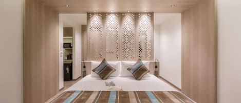 A hotel room with a large bed, a wooden headboard, and a decorative screen.