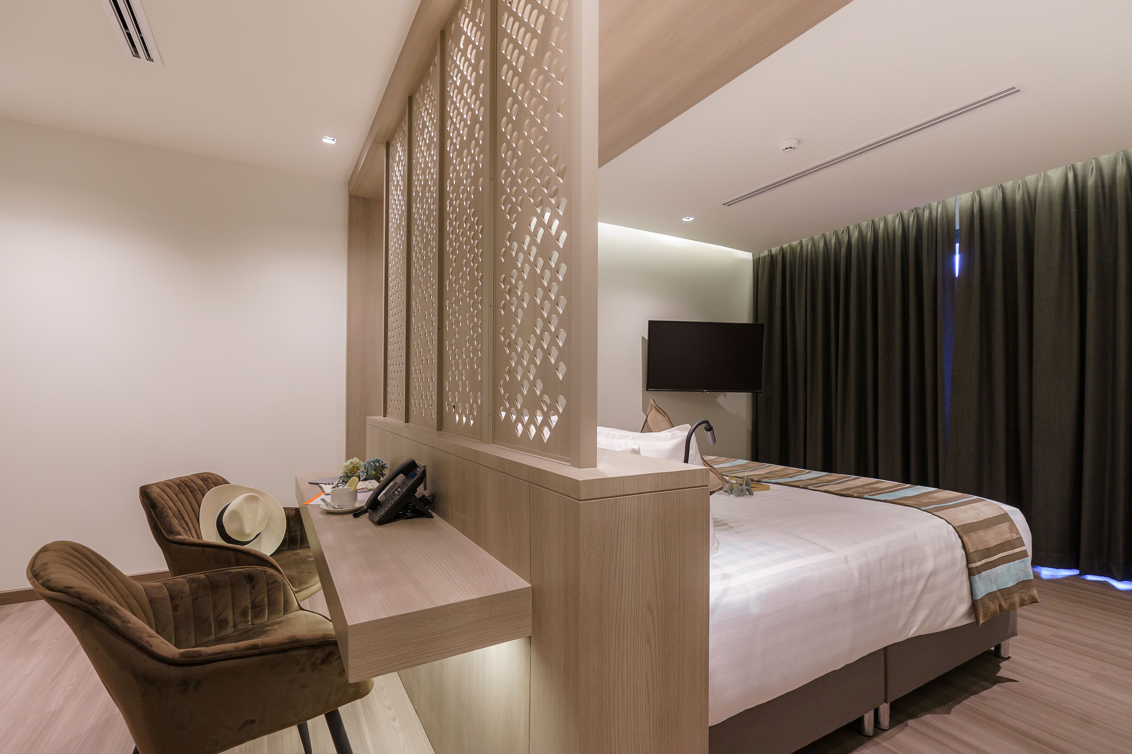 Une chambre d’hôtel comprenant un lit, un bureau avec un téléphone, deux chaises et un miroir.