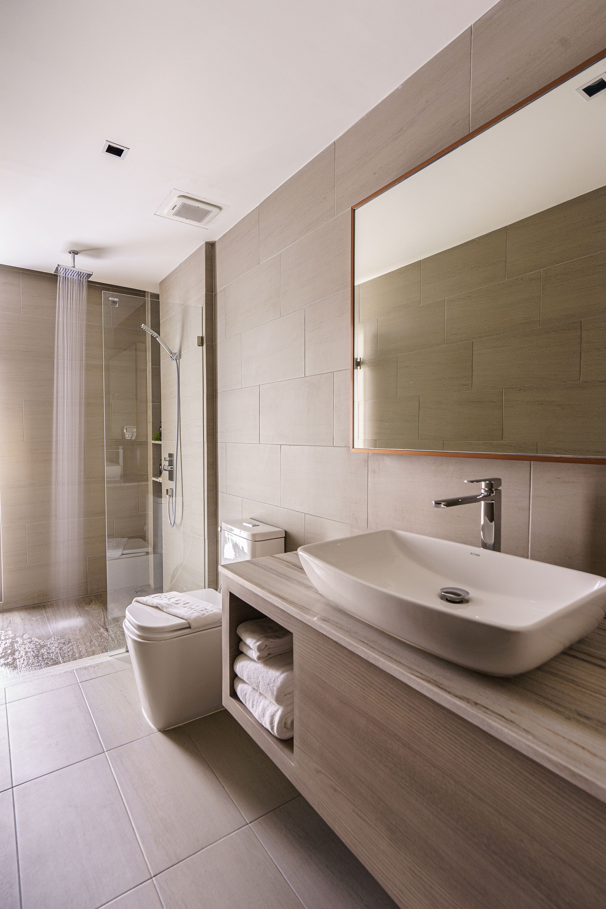 A modern bathroom with a glass shower enclosure, a white sink, and a large mirror.