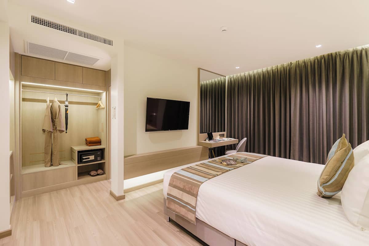 A hotel room with a bed, a TV, a desk, and a walk-in closet.