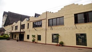 A building with a flat roof, multiple windows, and a paved courtyard. - The Headquarters Inn (Nairobi)