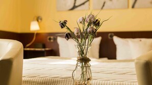 Une chambre d’hôtel avec un lit, un vase de fleurs et une télécommande sur la table de chevet.