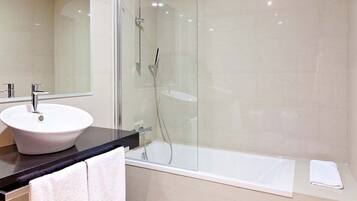 Une salle de bain moderne avec une douche à parois de verre, un lavabo blanc et une baignoire.
