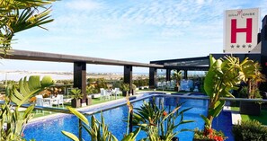 Un área de piscina en la azotea con vistas a la ciudad, un cartel que dice 'D.N.A. MONSE H' y mobiliario para estar al aire libre.