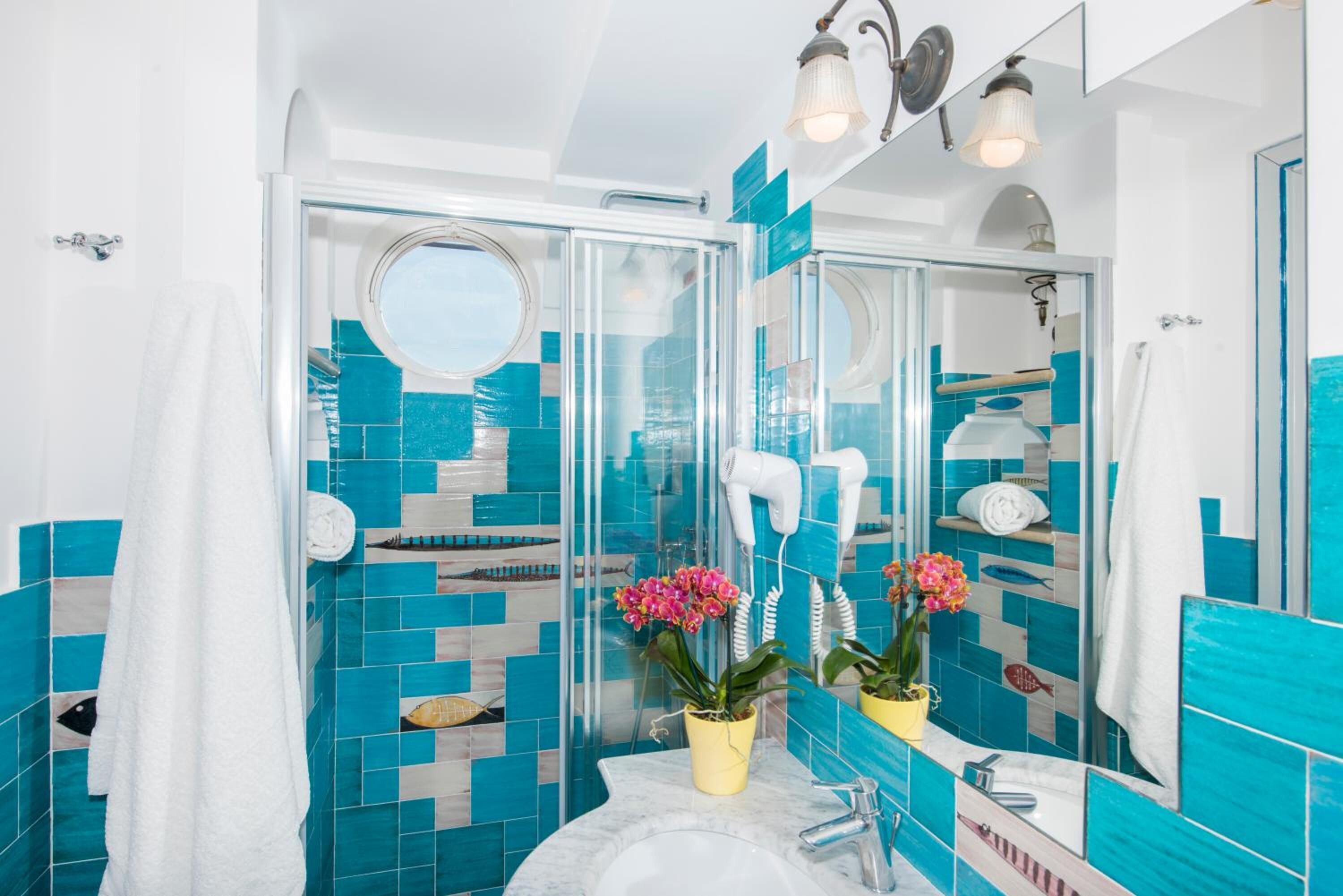A bathroom with a glass shower enclosure, a white sink, and a mirror.
