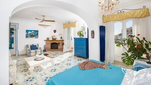 Ein geräumiges Zimmer mit einem großen Bett, einem Kamin, einer blauen Kommode und Blick auf die Stadt.