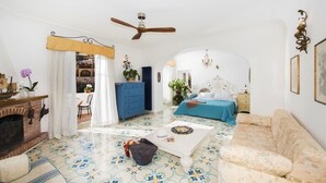 Ein geräumiges Wohnzimmer mit Kamin, einem blauen Sofa, einem weißen Sessel und einem gemusterten Boden.
