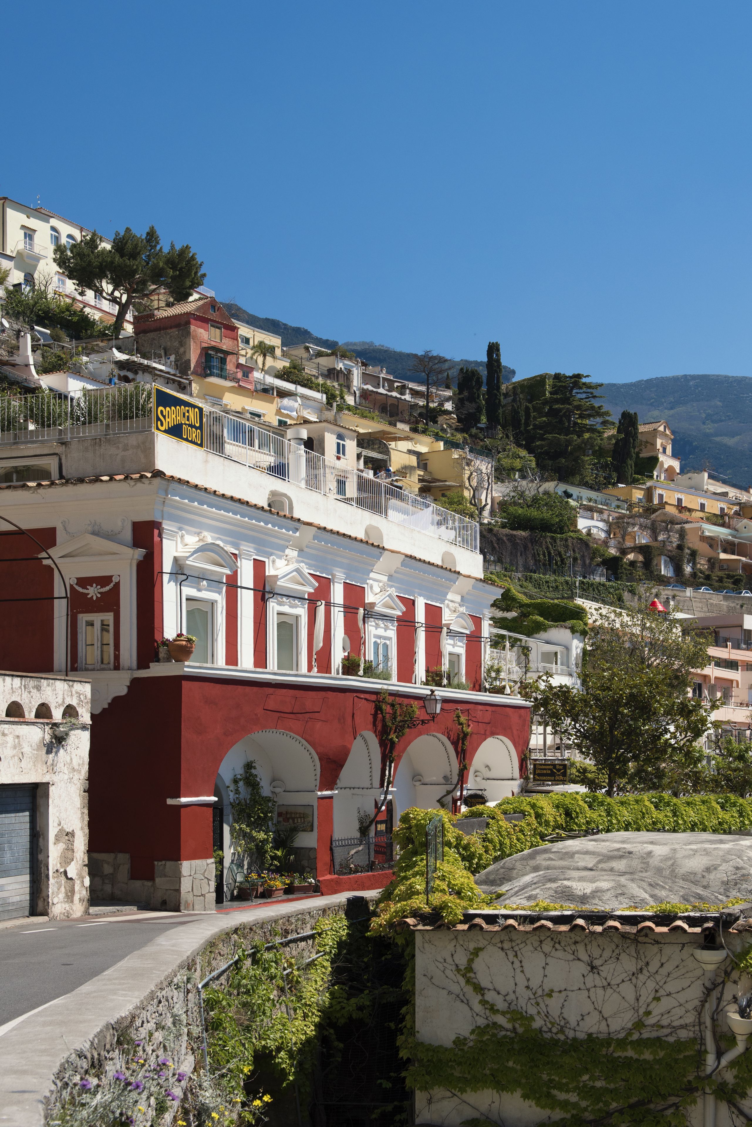Um edifício com fachada vermelha, arcos brancos e uma placa com o texto 'Sbarrodo Doro'.