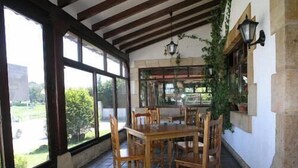A dining area with a wooden table and chairs, large windows, and a view of greenery outside. - Hotel Costa San Juan De La Canal (Santa Cruz de Bezana)