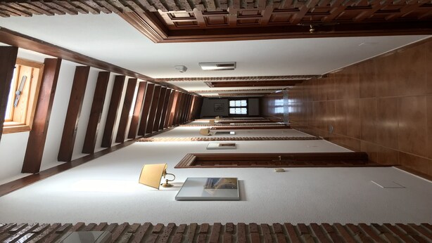 A long, narrow hotel corridor with wooden paneling, a small window, and a lamp on the floor. - Hotel Costa San Juan De La Canal (Santa Cruz de Bezana)