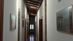A hallway with exposed wooden beams, brick walls, and a tiled floor. - Hotel Costa San Juan De La Canal (Santa Cruz de Bezana)