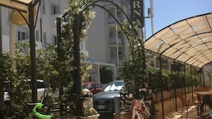 Zona de estar al aire libre cubierta con un letrero del Hotel Lucerna, bicicletas y coches estacionados.