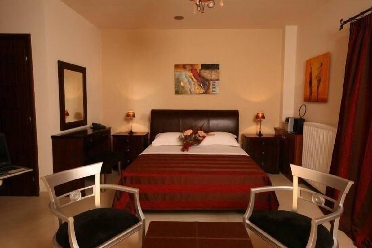 Een hotelkamer met een groot bed, twee nachtkastjes, een spiegel en een schilderij aan de muur.