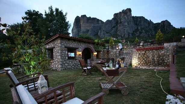 Un bâtiment en pierre doté d’un petit porche, d’un espace extérieur aménagé pour s’asseoir et offrant une vue sur des montagnes rocheuses.
