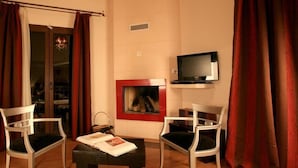 Un salon avec une cheminée, deux fauteuils, une table basse et un téléviseur.