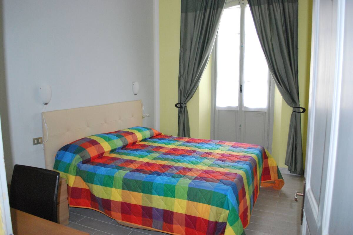 Une chambre à coucher avec un lit, une chaise et une fenêtre avec des rideaux.