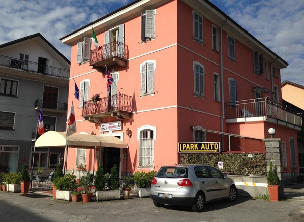 A pink building with a sign for 'PARK AUTO' and flags on balconies.