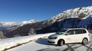 A white car with "Hotel Domodossola" branding parked on a snowy road with a mountainous backdrop. - Hotel Domodossola (Domodossola)