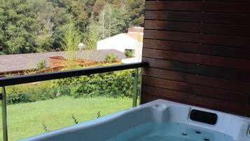 Un jacuzzi con vista a un paisaje verde y una terraza de madera.