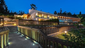 A modern hotel with a spacious lobby, a covered outdoor area, and a well-lit pathway.