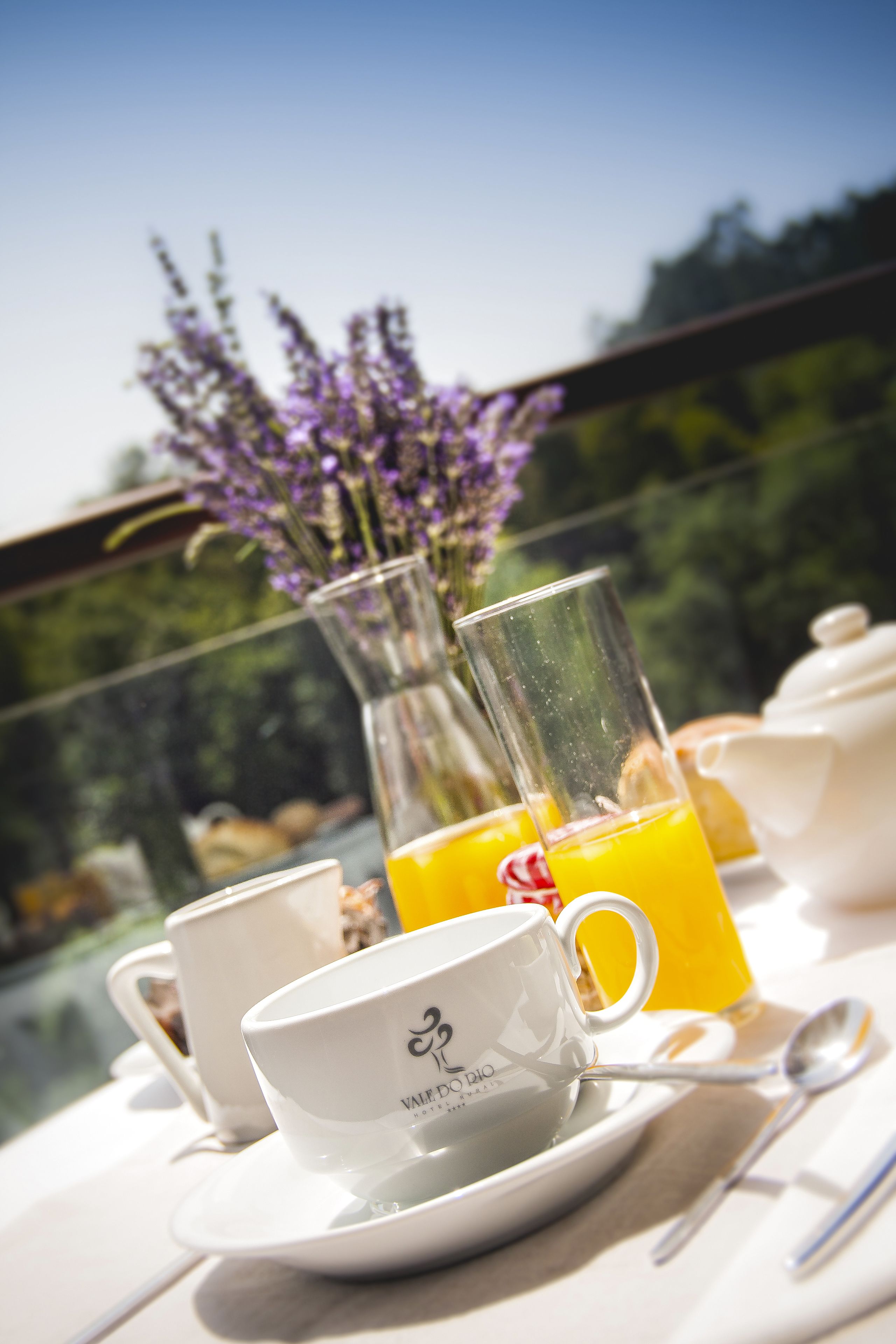 Ein Frühstückstisch mit Tasse, Untertasse, Löffel und einem Glas Orangensaft.