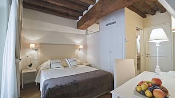 Un dormitorio con cama, mesitas de noche, armario, escritorio con fruta y lámpara.