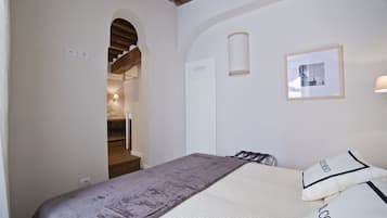 Ein Schlafzimmer mit einem Bett, einem gerahmten Bild an der Wand und einer Treppe zu einem anderen Raum.