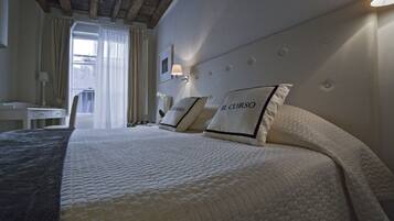 A hotel room with a large bed, a desk, and a window with curtains.