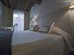 A hotel room with a large bed, a desk, and a window with curtains. - B&B Il Corso (Siena)