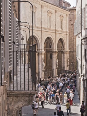 A crowded street with historic buildings and a prominent archway. - B&B Il Corso (Siena)