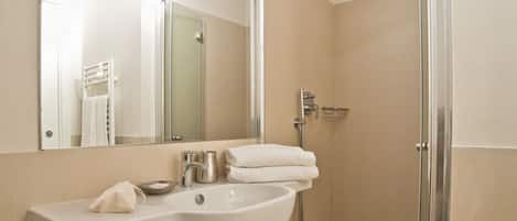 A modern bathroom with a large mirror, a sink, and a shower.