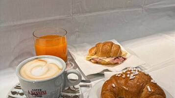 A breakfast setting with a cup of coffee, a glass of orange juice, and two croissants on a table.