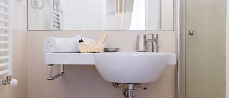A bathroom with a white sink, a mirror, a shower, and a toilet.