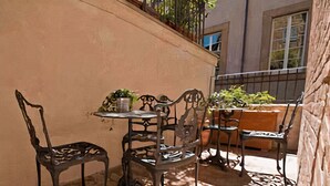 An outdoor patio with a table and chairs, a potted plant, and a wooden bench. - B&B Il Corso (Siena)