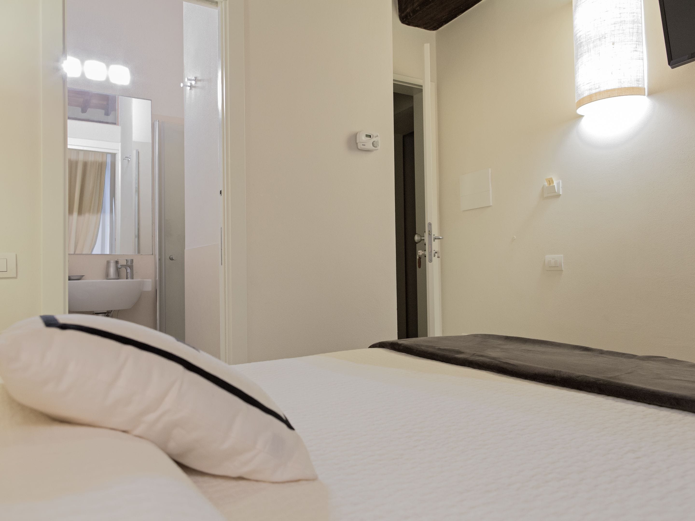 A hotel room with a bed, a bathroom with a sink and mirror, and a door leading to another room.