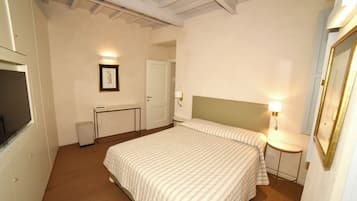 A bedroom with a bed, bedside table, lamp, and a framed picture on the wall.