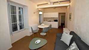 A compact living space with a dining area, kitchenette, and a sofa with cushions. - B&B Il Corso (Siena)