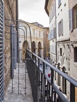 Una stretta via fiancheggiata da edifici, con finestre ad arco e un percorso pedonale.
