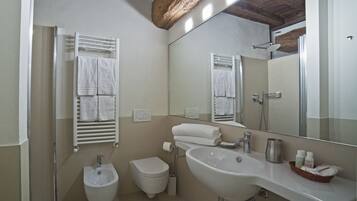 Een badkamer met een hygiëneschuimer, toilet, wastafel en een grote spiegel.