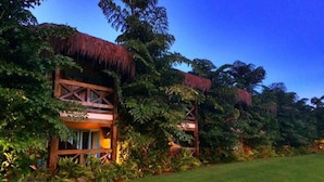 Un resort con edificaciones de techo de paja, abundante vegetación y un césped bien cuidado.