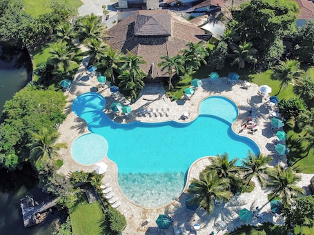 Una piscina al aire libre, sombrillas, sillones reclinables de piscina