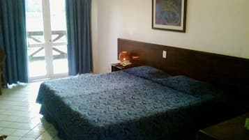 Un dormitorio con cama, mesita de noche, un cuadro enmarcado en la pared y una ventana con cortinas.