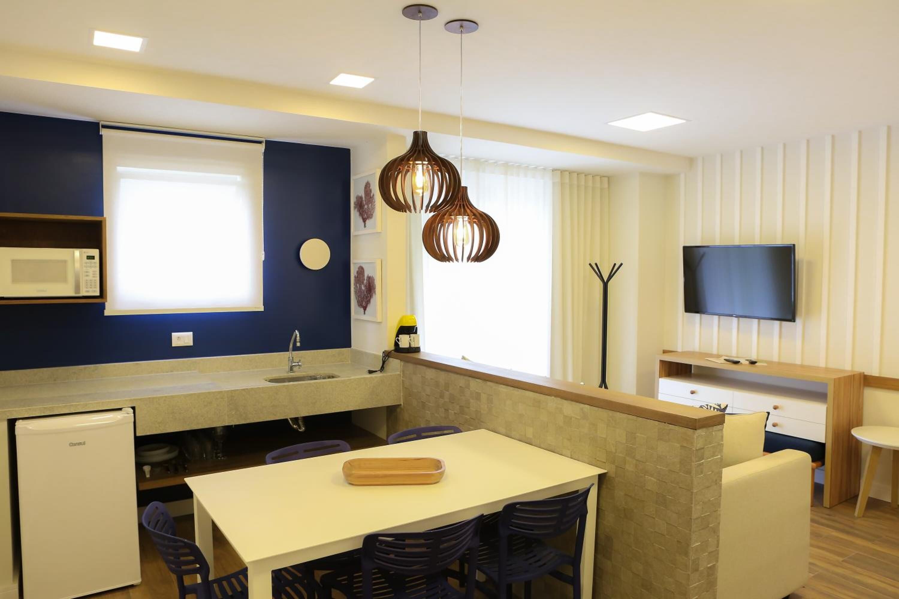A compact kitchen with a microwave, sink, and dining area with chairs and a table.
