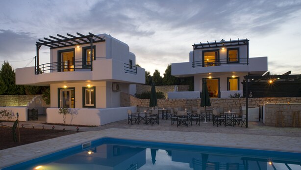 A modern two-story house with a swimming pool, outdoor seating, and stone walls. - Cavo Plako Villas (Sitia)