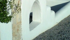 A modern building with a white exterior, a stone base, and a staircase leading to the entrance. - Cavo Plako Villas (Sitia)